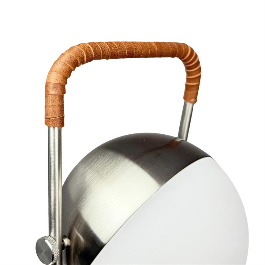 Table lamp with round, brushed steel body and white dome; a brown leather-wrapped curved handle is mounted above the top, depicted against a uniform white background.