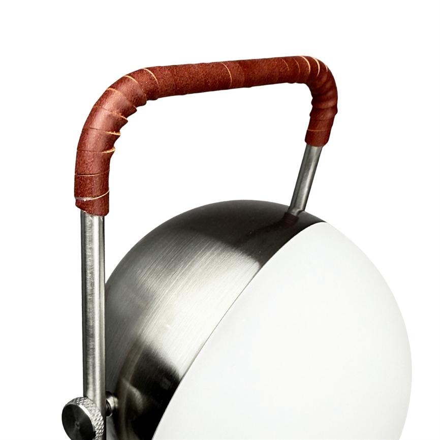 Lamp with round, brushed steel shade and white front, whose curved metal handles are wrapped in brown leather, set against a white studio background.