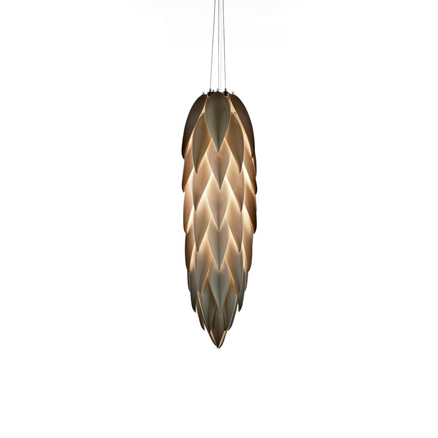 A long cone-like pendant lamp emits soft, golden light through overlapping leaf-shaped shades, suspended by thin cables against a neutral white background.